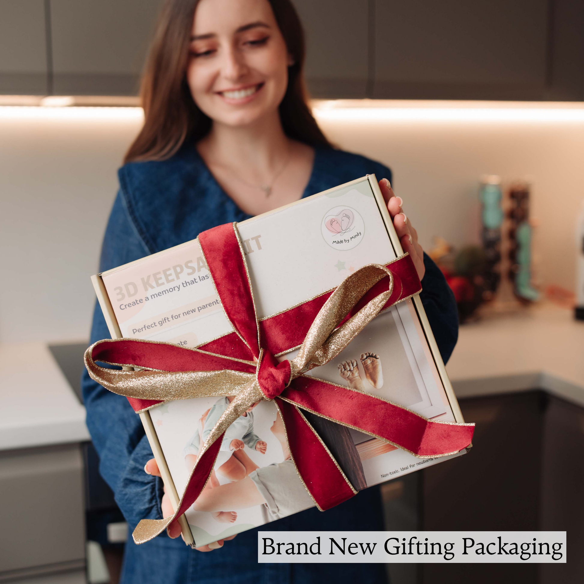 Woman holding a gift box with a red ribbon in a kitchen setting